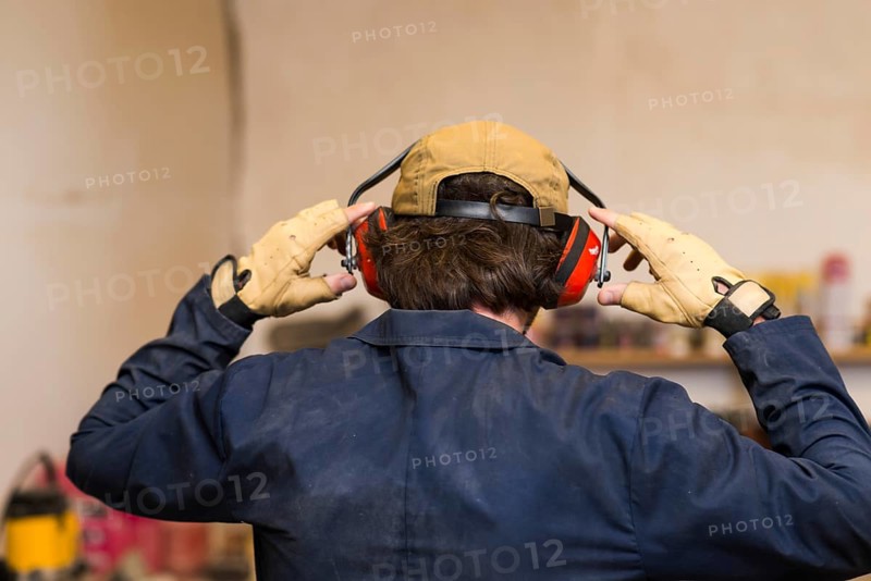 Rear view handyman wearing ear defender his ear