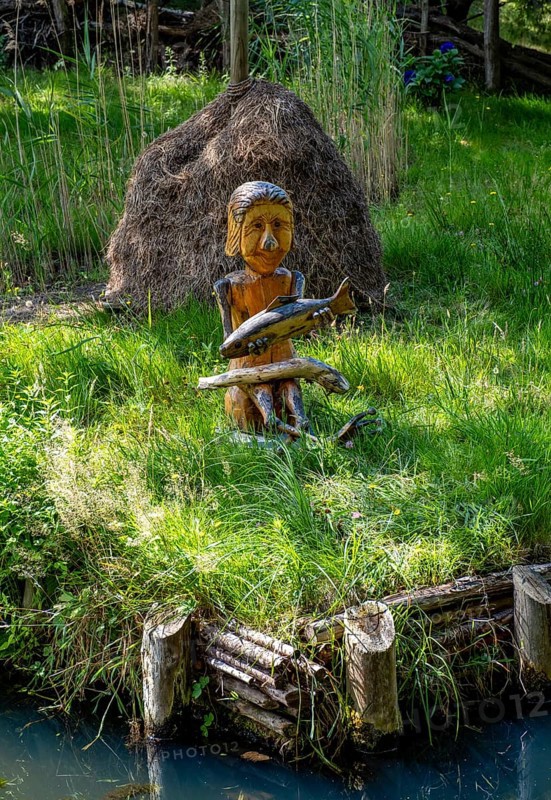 Wooden figure with fish in hands on the bank of the Spree
