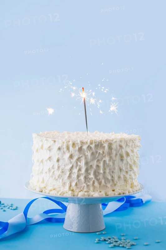 White birthday cake with burning sparkler