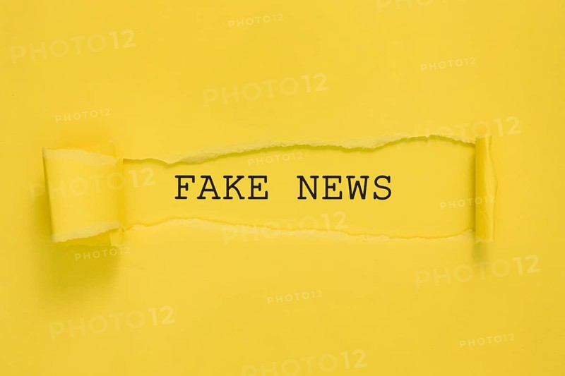 Torn fake news paper yellow wall