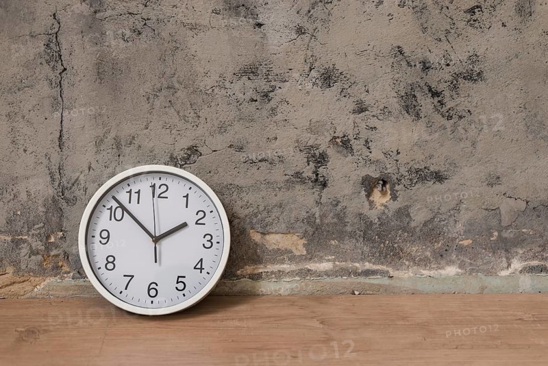 Clock wooden desk against weathered wall