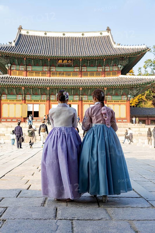 Young woman in traditional hanbok in front of the audience hall Injeongjeon Hall
