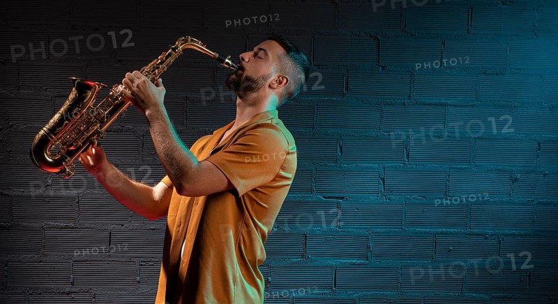 Male musician playing saxophone spotlight with copy space