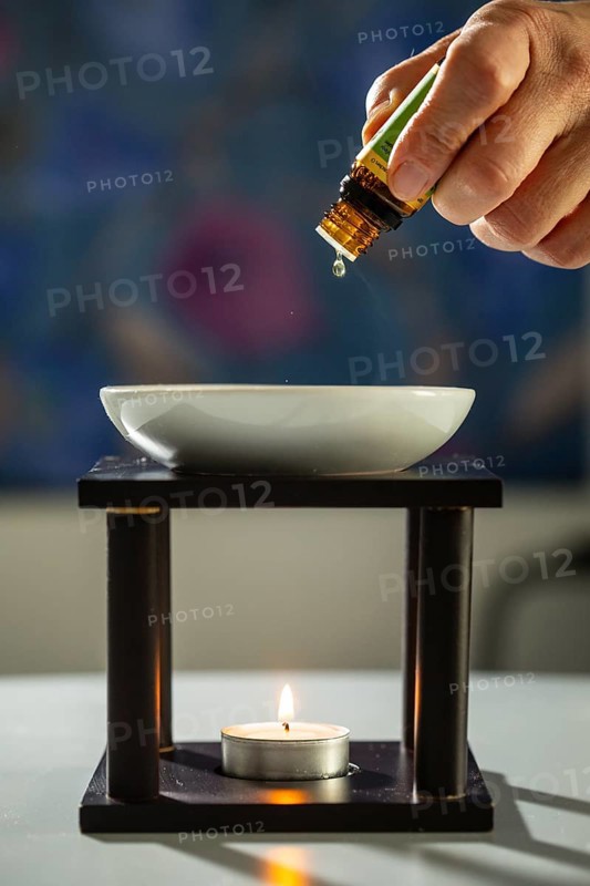 One person drips essential fragrance oil into a bowl