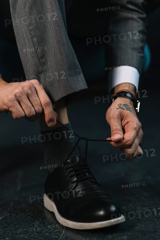 Low section businessman s hand tying shoelace