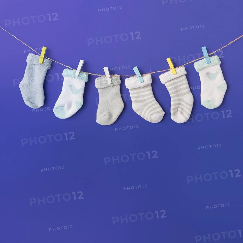 Different type baby s sock hang clothesline against blue backdrop