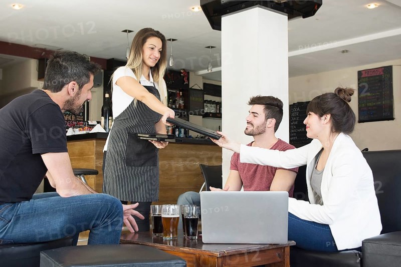 Waitress presenting menu female customer with friends bar