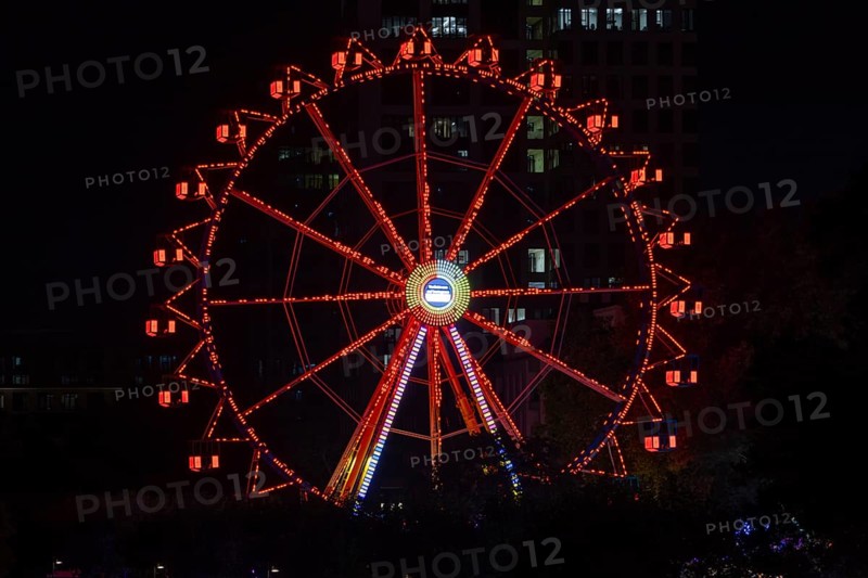 The red lights of the Ferris wheel at the Mainfest shine in the evening. The Mainfest on the Mainkai