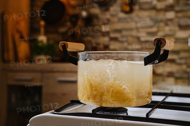 Cooking fettuccine pasta into boiling water in a transparent glass saucepan