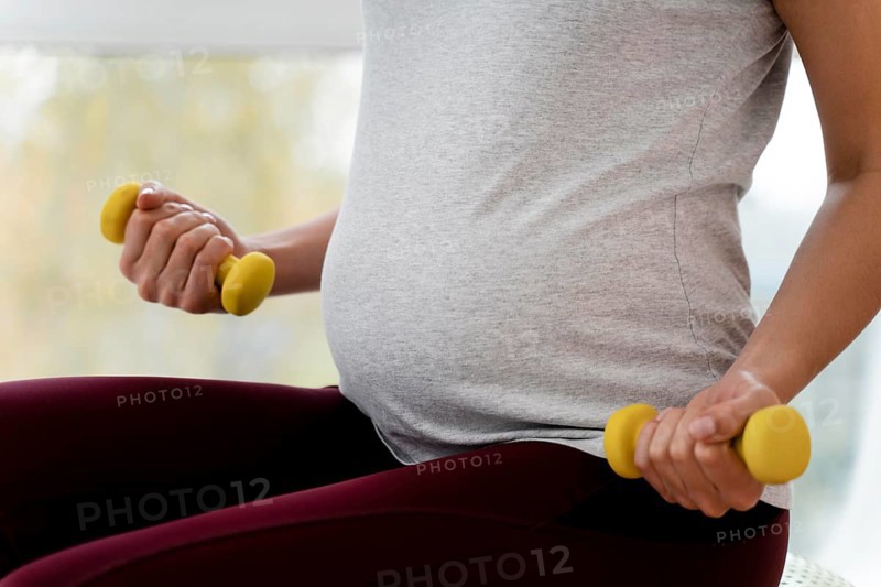 Pregnant woman using yellow weights
