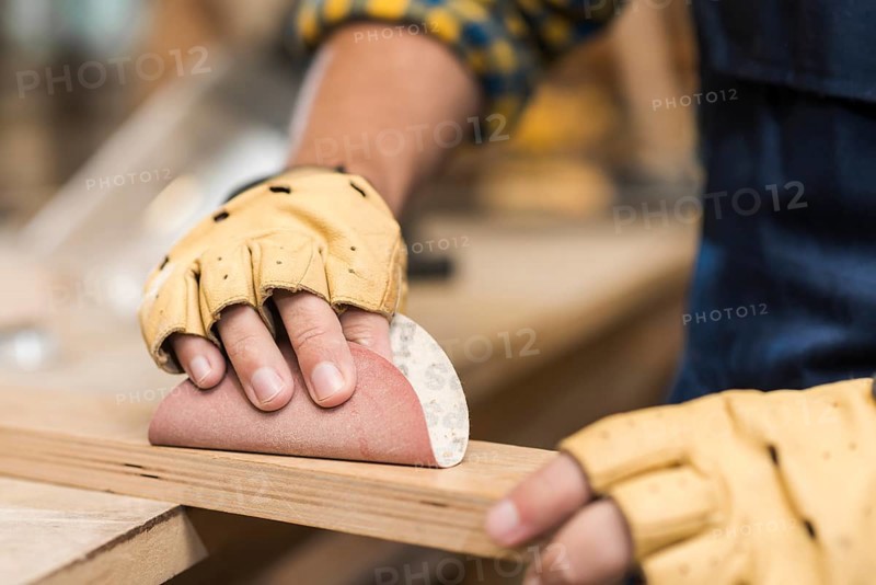 Close up male carpenter rubbing down wood with sandpaper
