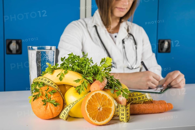 Fresh fruits with measuring tape front female dietician writing clipboard