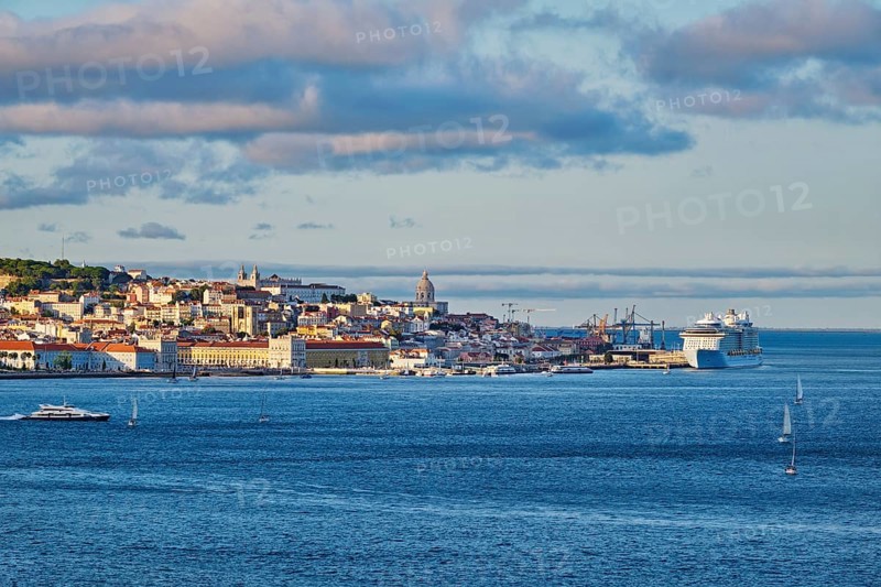 View of Lisbon over Tagus river from Almada with yachts tourist boats and passenger ferry and moored cruise liner on sunset with dramatic sky. Lisbon
