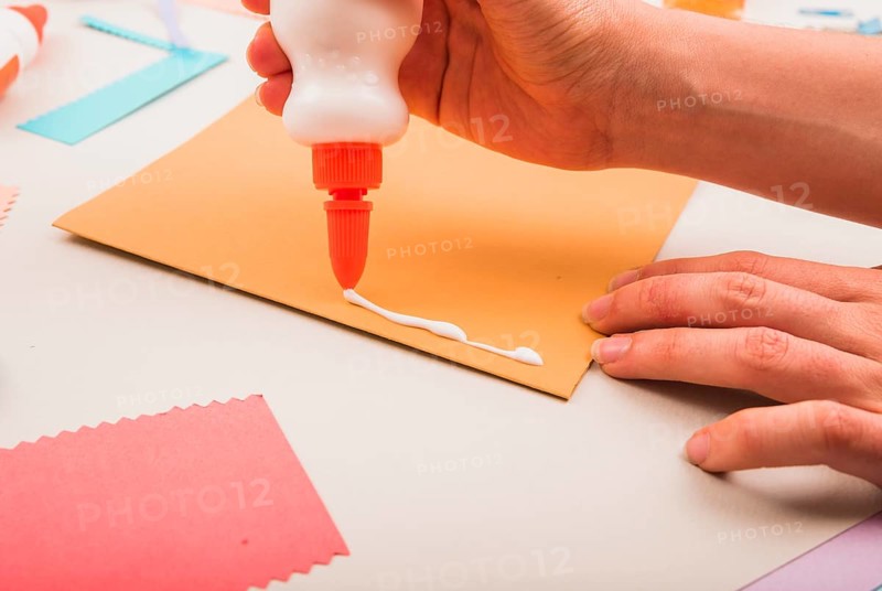 Close up person s hand applying white glue paper