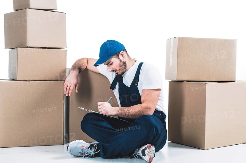Courier writing clipboard near parcels