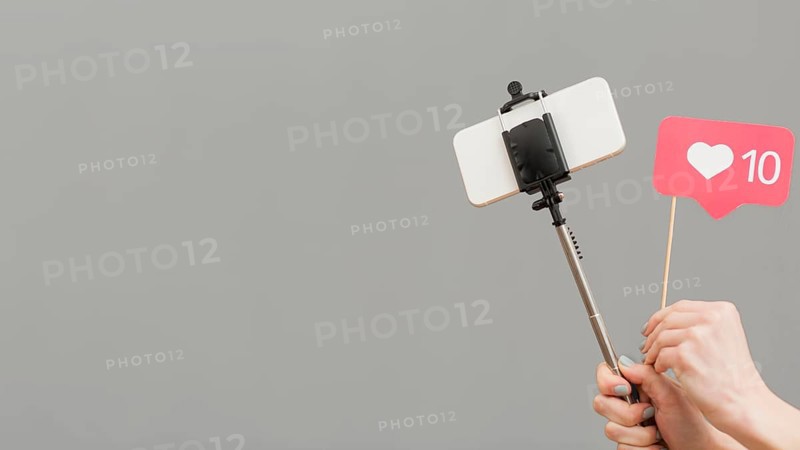 Close up blogger holding selfie stick with mobile phone