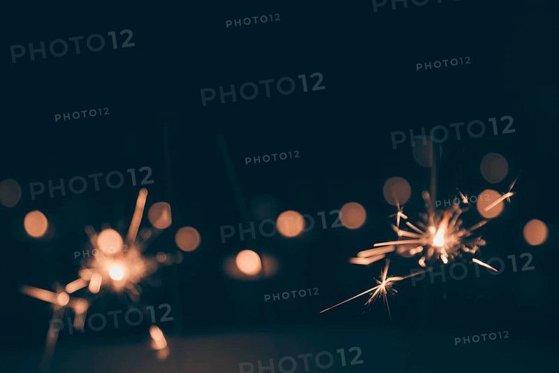 Sparklers burning dark bokeh background