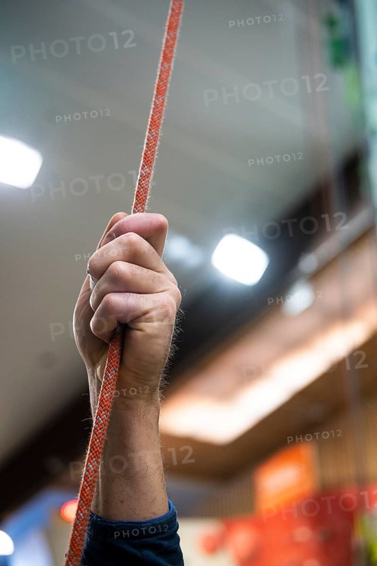 A person holding a rope for belaying in a climbing gym