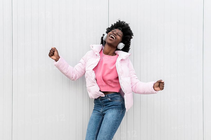Portrait young woman with headphones jumping