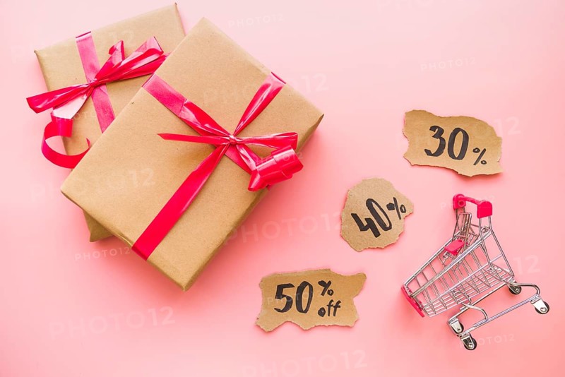 Gift boxes with red bows near shopping trolley