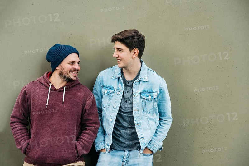 Young friends standing near grey wall