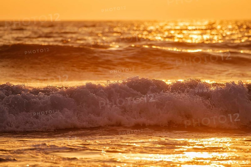 Breaking ocean wave on sunset backlit with sun. Fonte da Telha