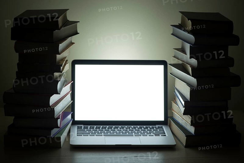 Laptop dark stacked books