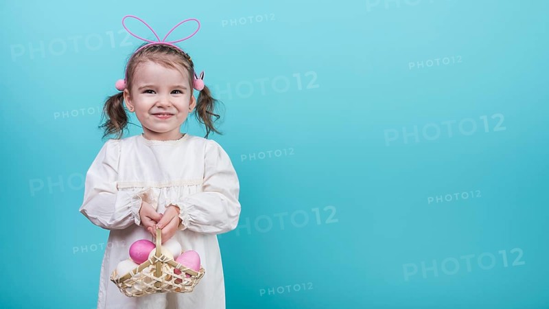 Little girl bunny ears holding basket with easter eggs