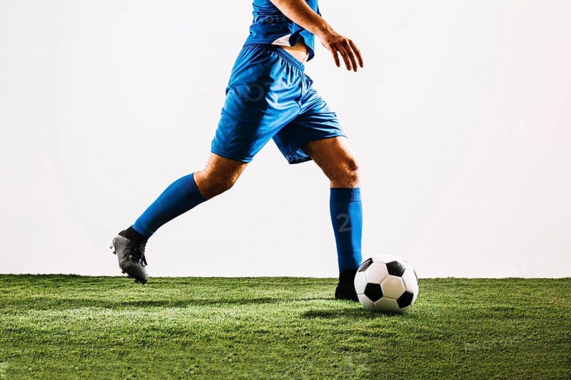 Crop football player shooting ball