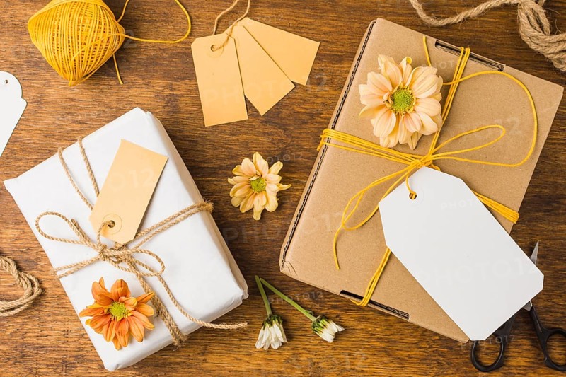 Wrapped gift tied with tag string beautiful flower wooden surface