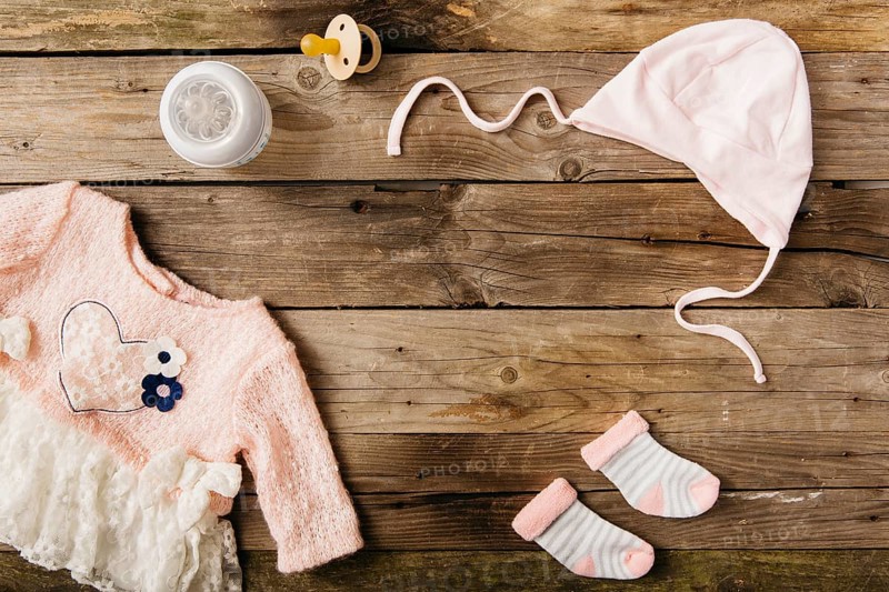 Pink baby s dress with headwear pair socks milk bottle pacifier wooden table