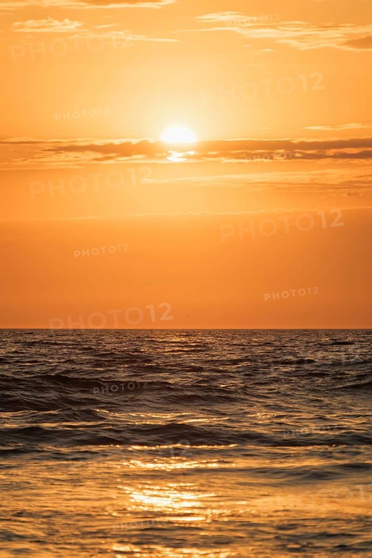 Ocean waves on sunset with setting sun background