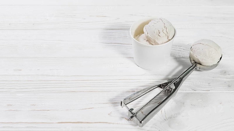 Scoop with ice cream ball near cup