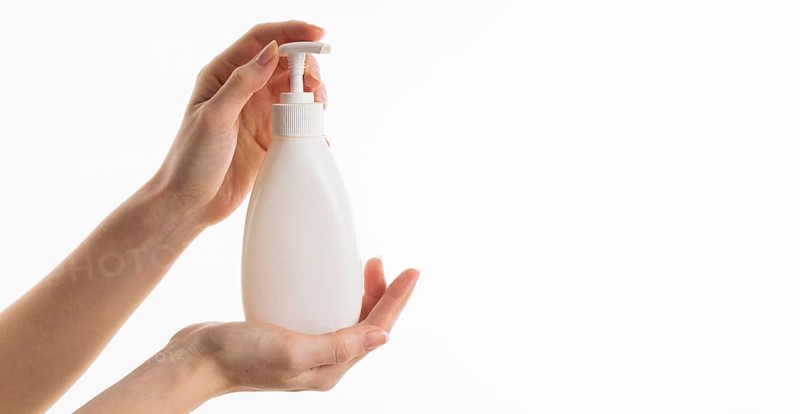 Hand holding liquid soap bottle with copy space