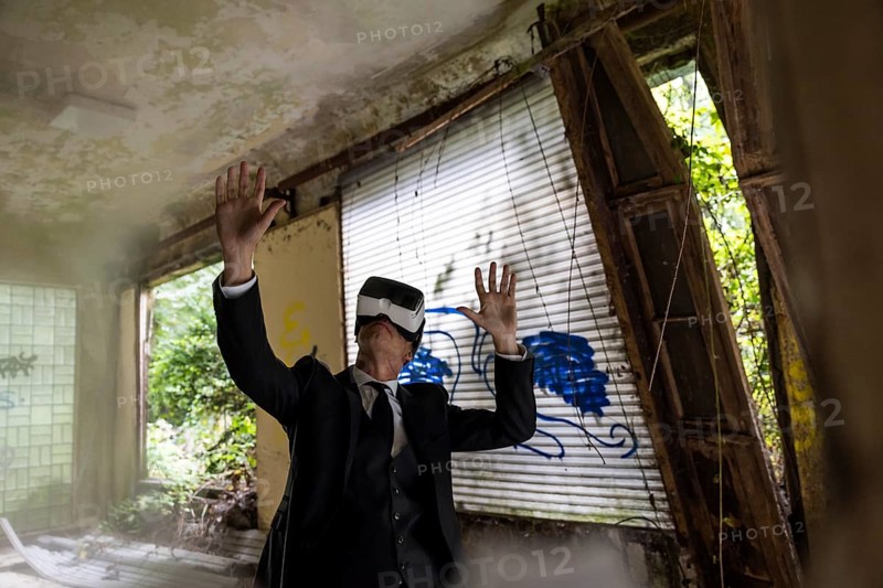 Man dressed in suit wearing VR glasses in a dilapidated office building