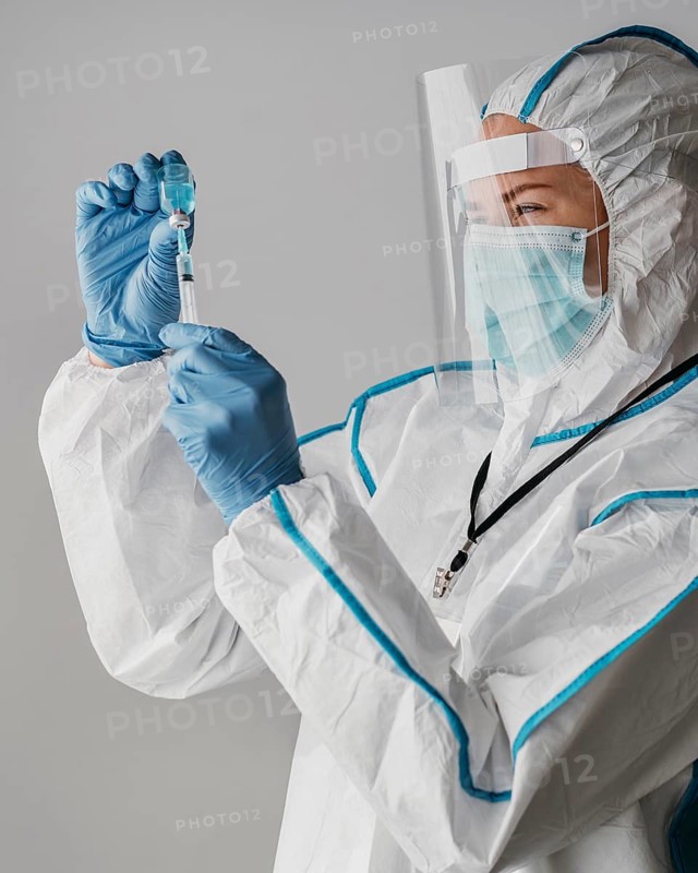 Doctor holding vaccine bottle while wearing protective equipment