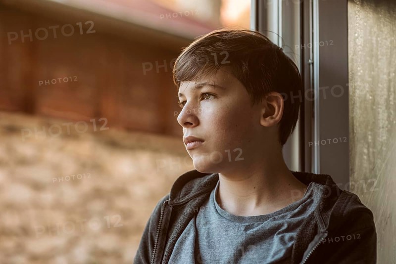 Side view sad boy looking outside