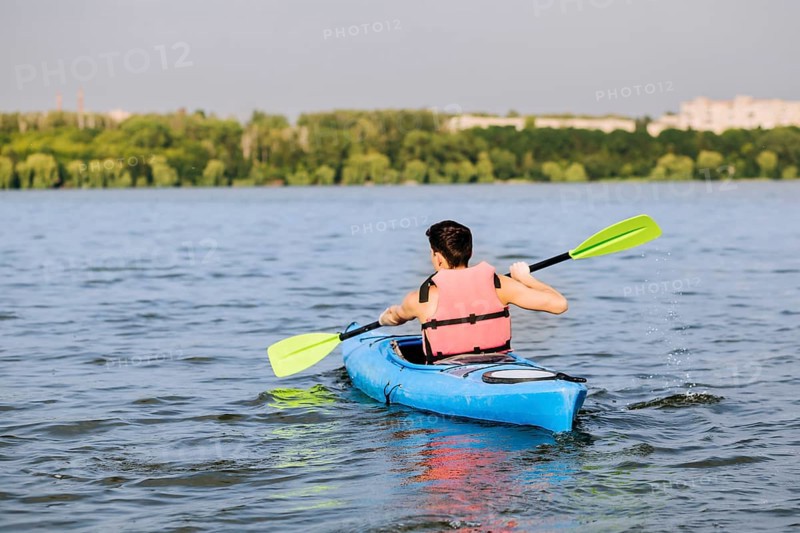 Rear view man using paddle kayaking