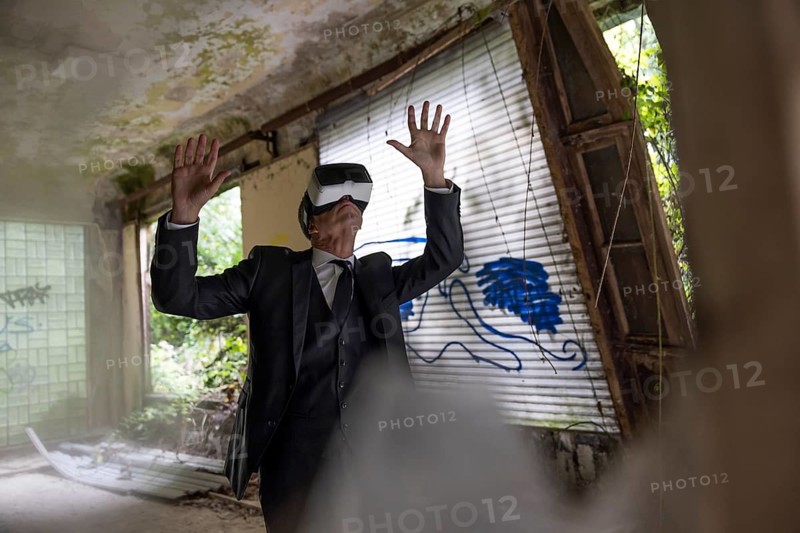Man dressed in suit wearing VR glasses in a dilapidated office building