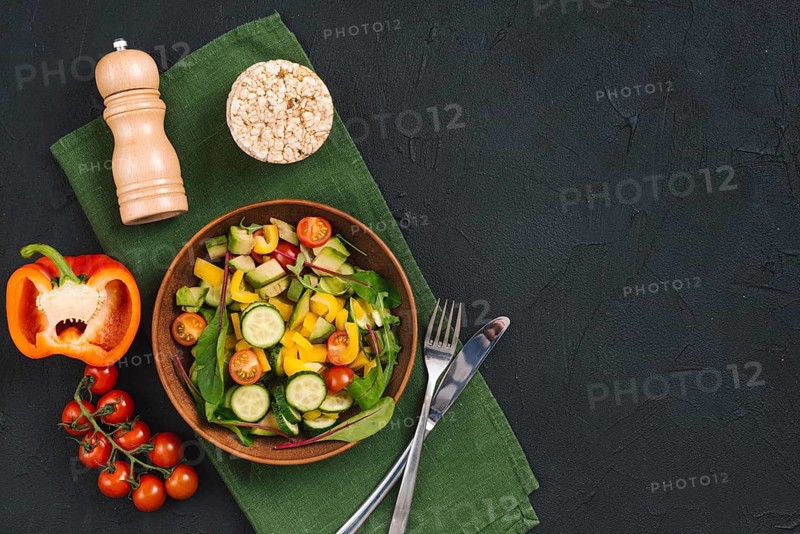 Rice puffed cake vegetables salad pepper shakers napkin black concrete textured backdrop