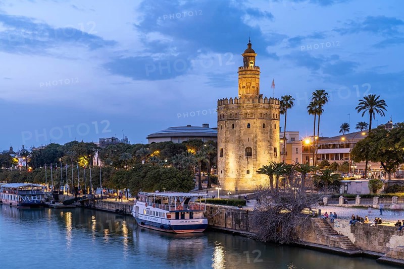 On the banks of the Guadalquivir River with the historic Torre del Oro tower at dusk