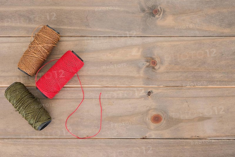 Red brown green yarn spool wooden table