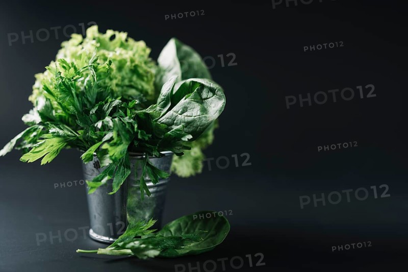 Organic leafy vegetables bucket black background