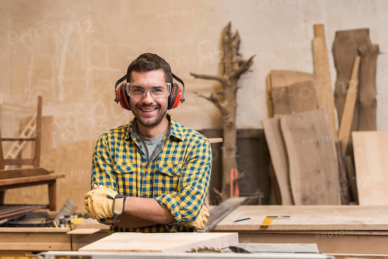 Portrait smiling carpenter wearing safety glasses ear defender workshop