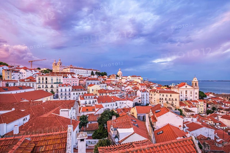 View of Lisbon famous view from Miradouro de Santa Luzia tourist viewpoint over Alfama old city district on sunset with dramatic overcast sky. Lisbon