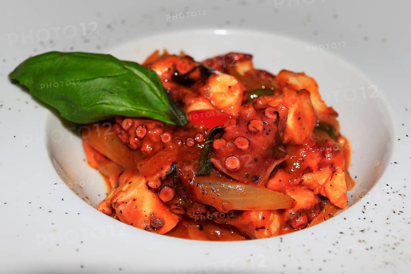 Octopus in red sauce on white plate