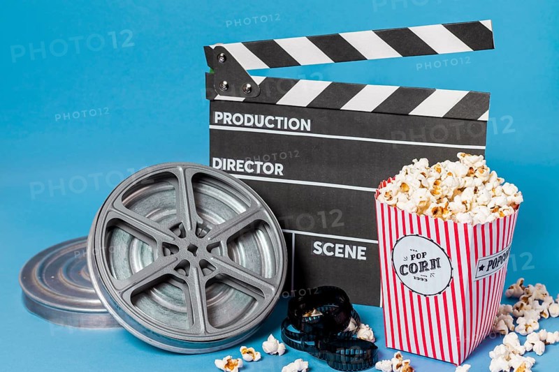 Film reels film strips clapperboard with popcorn box blue background