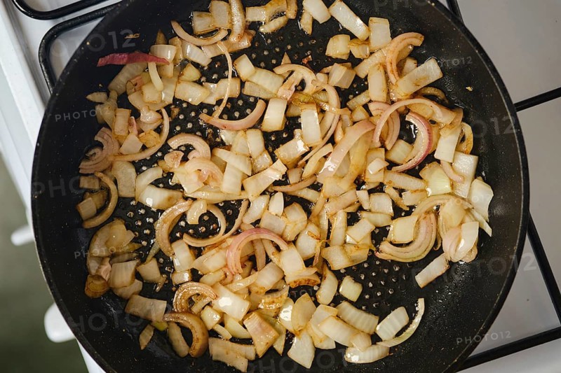 Frying shallots onion in a pan on a gas stove