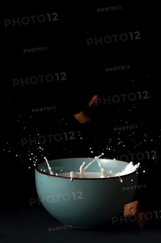 Cereals falling on a bowl with splashing milk