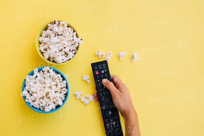 Crop hand remote control near popcorn